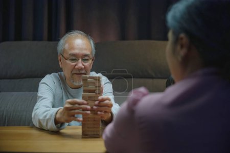 Photo for Happy grandparents Asian family enjoy playing toy block with little daughter together in home living room at night time, Smiling parent having fun play build constructor tower of wooden blocks - Royalty Free Image