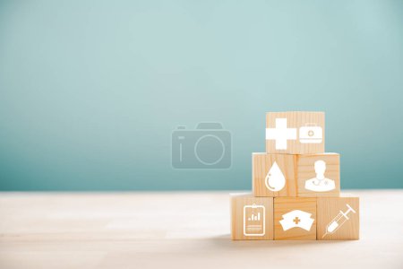 Téléchargez les photos : Soins de santé et assurance illustrés par une pyramide de cubes en bois. En haut, une icône d'assurance médicale sur fond blanc, laissant place au message d'assurance maladie. - en image libre de droit