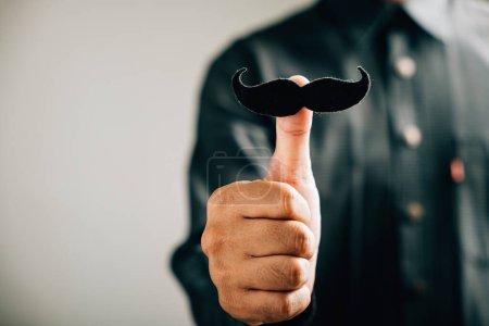 Téléchargez les photos : Un pouce d'homme tient une moustache, signifiant un soutien aux personnes touchées par le cancer de la prostate une image puissante pour les soins de santé pour hommes et la Journée mondiale du cancer. - en image libre de droit