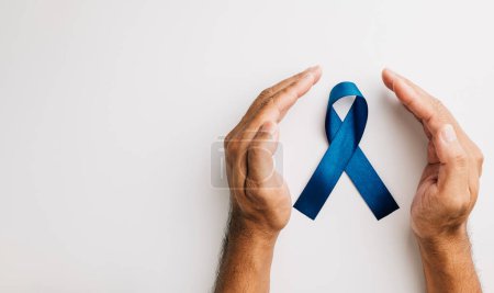 Téléchargez les photos : En novembre, un ruban bleu tenu dans les mains signifie que les hommes sont sensibilisés à la santé, en mettant l'accent sur le cancer de la prostate. Un rappel poignant pour les familles comme pour les patients. - en image libre de droit