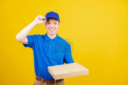 Photo for Portrait excited delivery service man standing he smile wearing blue t-shirt and cap uniform hold give food order pizza cardboard boxes looking to camera, studio shot isolated on yellow background - Royalty Free Image