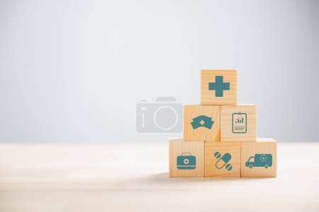 Téléchargez les photos : Image symbolique de la santé et de l'assurance dépeinte à travers une pyramide de cubes en bois. icônes médicales sur le dessus signifient la sauvegarde de la santé. Fond bleu avec copyspace pour la messagerie de l'assurance maladie. - en image libre de droit