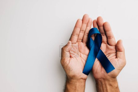 Téléchargez les photos : En novembre, un ruban bleu, symbolisant la santé des hommes et la sensibilisation au cancer de la prostate, est tenu dans les mains sur un fond blanc. Un rappel poignant pour tous, en particulier les pères. - en image libre de droit