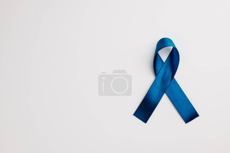 Photo for A shiny blue ribbon, symbolizing world diabetes day on November 14, stands out against a white background. Copy space for messages of support and care. - Royalty Free Image