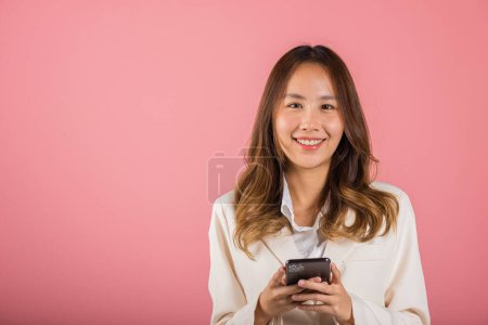 Téléchargez les photos : Female surprised and sms chatting internet online on smartphone studio shot isolated on pink background, Happy Asian portrait beautiful cute young woman teen smiling excited hold smart mobile phone - en image libre de droit