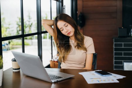 Photo for Asian business woman suffering from neck ache pain caused by long time laptop usage, Tired office woman sitting at desk touching massaging stiff neck while holding her head in cafe coffee shop - Royalty Free Image