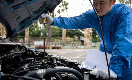 Photo for Man mechanical specialist professional checking oil level in car engine with tool on the road. Maintenance, safety, open supported hood auto. Side view of mechanic checking engine oil with open hood - Royalty Free Image