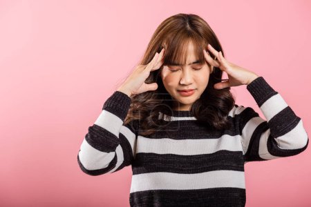 Téléchargez les photos : Portrait of beautiful Asian young woman sad tired strain face holding hold head by hands, stress female person unhappy closed eyes problem she headache, studio shot isolated on pink background - en image libre de droit