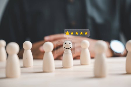 Photo for Wooden figure representing customer service rating. Hand picked in crowd of people. HR management selects positive leader with happy and smiling face to lead team towards success in business concept. - Royalty Free Image