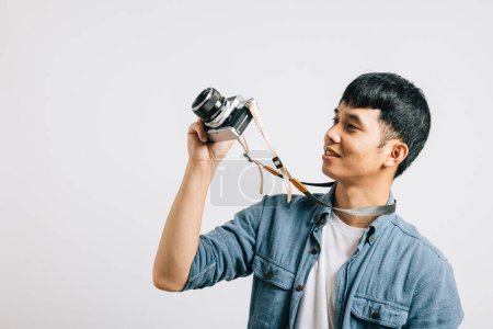Photo for Charismatic young man smiles for a photographer with a vintage camera. Studio shot isolated on white background. This snapshot embodies the essence of glamour and fun. - Royalty Free Image