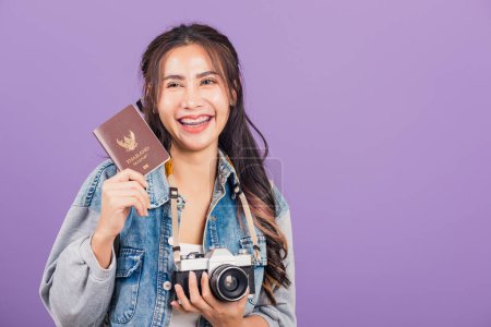 Photo for Happy Asian portrait beautiful young woman excited smiling in summer vacation holding passport and vintage photo camera, Thai female ready travel trip looking at camera isolated on purple background - Royalty Free Image