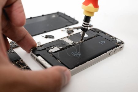 Photo for Technician repairing inside the smartphone motherboard with tools for recovery, The man repair by tightening nut from mobile phone with a screwdriver to fix problem - Royalty Free Image