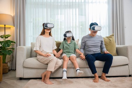 Photo for Happy family have mother father and daughter watching movie or playing video game, game entertainment innovation technology, Asian family wear vr glasses headsets excited sitting sofa in living room - Royalty Free Image
