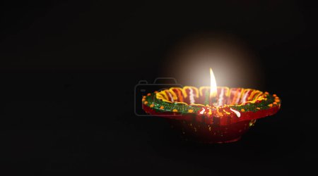 Foto de En el espíritu de Diwali, vibrantes lámparas de arcilla diya, símbolos de prosperidad y felicidad, arrojan su brillo sobre un tranquilo fondo negro. Perfecto para invitaciones, superposiciones de texto y arte abstracto. - Imagen libre de derechos