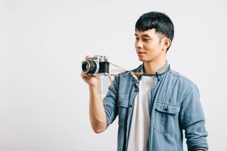 Photo for Excited young man smiles as a professional photographer takes his picture with a vintage camera. Studio shot isolated on white background. Glamorous paparazzi moment captured - Royalty Free Image