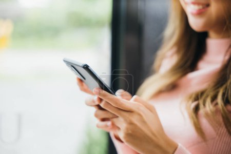 Photo for Young woman typing text message on smart phone device apps in cafe, beautiful female holding cellphone in hands and chatting social network with friends or reading email, mobile phone - Royalty Free Image