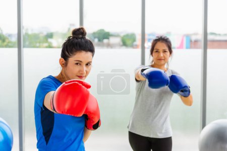 Téléchargez les photos : Style de vie asiatique adulte et jeune femme souriant sport fitness boxer portant des gants pratiquant coup de pied sur la boxe dans les vêtements de sport travailler en studio de yoga d'intérieur, sport sain concept d'entraînement - en image libre de droit
