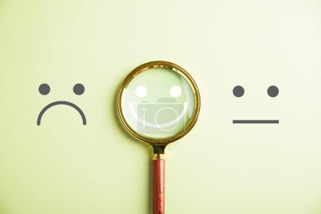 Photo for Magnifier glass reveals smiley face icon for finding happiness amidst sadness. Customer satisfaction and evaluation after service or marketing survey. Magnifying, satisfaction, reputation emphasized. - Royalty Free Image