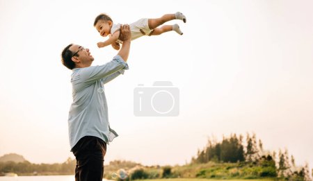 Photo for Playful family moment, father holds happy little boy up high, throwing up in sky on his birthday. cheerful child enjoys moment of freedom and joy, while the loving dad captures precious memory forever - Royalty Free Image