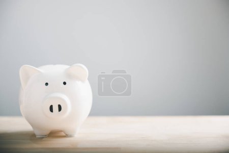 Photo for Cute white piggy bank rests on a desk. Symbolic of savings, success, and financial security. Its ceramic design concept of safe money storage, making visual representation of dreams and achievements. - Royalty Free Image