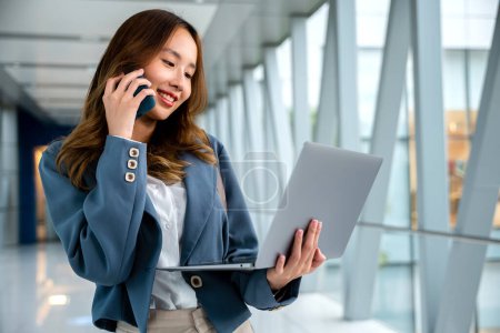 Photo for Professional woman using laptop and cellphone to multitask in airport, staying connected while traveling - Royalty Free Image