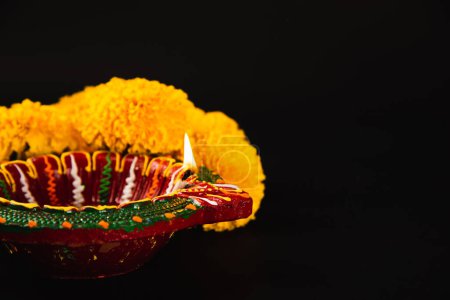 Téléchargez les photos : Célébrez le festival indien Diwali, une lampe Diwali magnifiquement conçue et des rangoli de fleurs complexes ornant un fond noir dramatique. Idéal pour les invitations à Diwali, les mariages et les cérémonies religieuses. - en image libre de droit