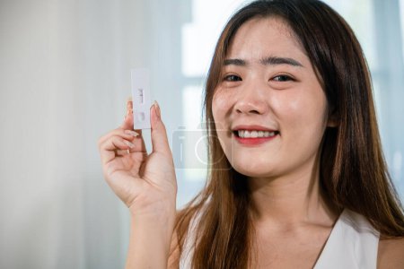 Photo for Close up woman showing rapid antigen test kit for selftest with Negative result during swab COVID-19 testing, female holding perform fast coronavirus ATK self test at home in living room, nasal - Royalty Free Image