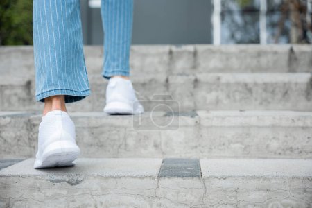 Photo for With determination, a woman in sneakers takes on the city stairs, reflecting her relentless progress. Every step symbolizes her commitment to success and ongoing growth. step up - Royalty Free Image