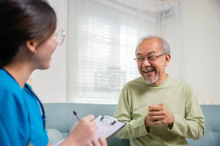 Téléchargez les photos : Asiatique jeune infirmière écrivant prescription lors de la visite à domicile vieillard malade, homme âgé prend médecin à la maison racontant les plaintes de santé, les soins de santé et le concept médical - en image libre de droit