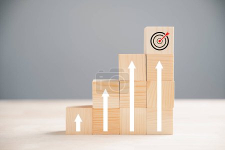 Photo for Cube wood blocks featuring prominent Target icon and rise up arrows. Bar graph chart steps on vertical background signify business growth process, emphasizing profit, investment, economic improvement - Royalty Free Image