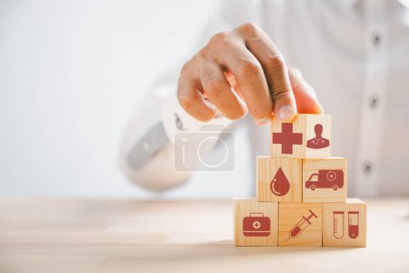 Photo for Wooden block with healthcare and medical icons held by hand, symbolizing safety, health, and family well-being. Representing pharmacy, heart care, and happiness. health care concept - Royalty Free Image