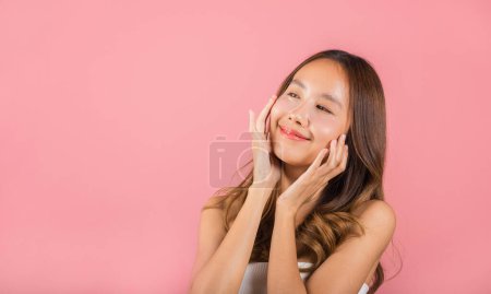Foto de Feminidad. Asiática hermosa mujer joven sonriente máscara parches cosméticos gel debajo de los ojos, Retrato femenino tocando piel limpia parche médico hidrogel en la cara, aislado sobre fondo rosa, cuidado de la piel - Imagen libre de derechos