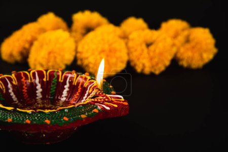 Téléchargez les photos : Diwalis beauté révélée, Une lampe Diwali magnifiquement ornée et rangoli fleur ornée sur une toile de fond noir dramatique. Idéal pour les invitations festives, les cérémonies et les célébrations. - en image libre de droit
