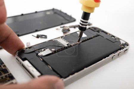 Photo for Technician repairing inside the smartphone motherboard with tools for recovery, The man repair by tightening nut from mobile phone with a screwdriver to fix problem - Royalty Free Image