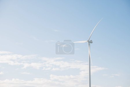 Foto de Un ángulo pintoresco de turbinas de molinos de viento en una granja de montaña encarna la innovación de energía limpia. La industria eólica moderna impulsa el desarrollo sostenible en el contexto de un cielo azul claro. - Imagen libre de derechos