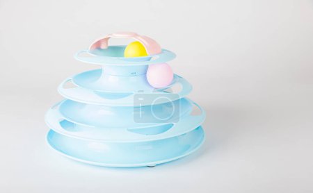 Photo for The white backdrop highlights a blue cat tower toy, circular turntable, and a cats paw gripping a moving ball. Its all about feline intelligence and hunter instincts during playtime. - Royalty Free Image