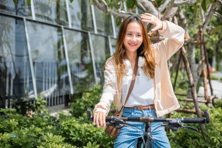 Foto de En medio de la ciudad una joven alegre protege del sol caliente en su bicicleta capturando la belleza de la diversión al aire libre y la moda. Esta temporada es todo sobre la felicidad y la naturaleza. - Imagen libre de derechos