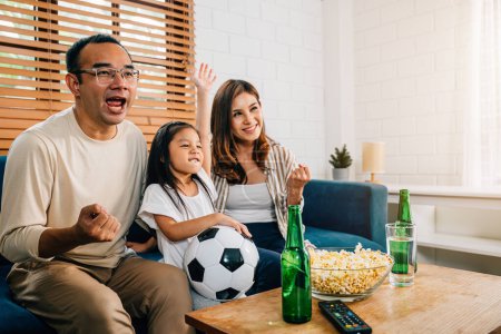 Téléchargez les photos : Une famille heureuse de fans aime regarder un match de football à la télévision à la maison, créant une atmosphère de convivialité et de liens. Leurs acclamations et leurs sourires reflètent la joie du jeu et le bonheur partagé. - en image libre de droit