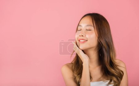 Foto de Anti aging. Asian beautiful young woman smiling mask cosmetic patches gel under the eyes, Portrait female applying medical hydrogel eye patch on face, studio shot isolated on pink background, skincare - Imagen libre de derechos