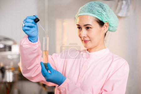 Photo for In juice beverage factory woman food engineer showcases food and beverage quality and safety testing concepts by utilizing test tubes for sampling basil or chia seeds in bottled products. - Royalty Free Image