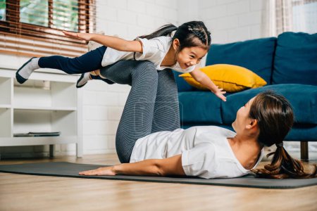 Photo for In a heartwarming family fitness session a mother and her child find joy in pretending to fly like airplanes while practicing Pilates and yoga promoting trust harmony and happiness. - Royalty Free Image