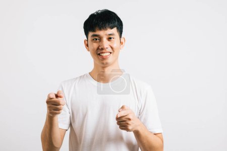 Photo for A cheerful Asian man excitedly makes a two-gun gesture to the camera with a friendly and cheeky expression. Isolated on white background, he exudes positivity and joy. - Royalty Free Image