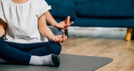 Téléchargez les photos : Une mère et sa fille trouvent la joie dans le yoga familial assis en position de lotus et se concentrant sur la pleine conscience et la méditation créant un moment de famille harmonieux et joyeux à la maison. - en image libre de droit