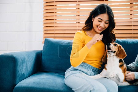 Photo for In an affectionate family portrait, a woman and her mother enjoy a bonding session with their Beagle dog on the sofa. Their love and loyalty shine through in their smiles. Pet love - Royalty Free Image