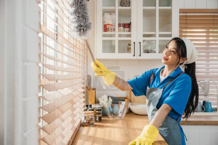 Photo for Woman enjoys cleaning dirty window blinds ensuring hygiene. Holding duster and whisk for routine housework. Modern cleaning for a clean home is portrayed. whisk - Royalty Free Image