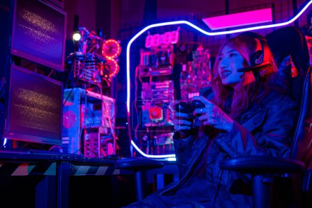 Foto de Gamer usando controlador de joystick para juegos de torneos virtuales videojuegos en línea con luces de neón de computadora, mujer usa auriculares para juegos jugando en vivo esports juegos de consola sala de juegos - Imagen libre de derechos