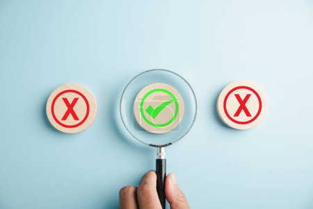 Photo for Hand holding magnifying glass signifies business choices, yes or no mark depicts difficulty. Successful decision represented by hand selection and check mark icon. Think With Yes Or No Choice. - Royalty Free Image