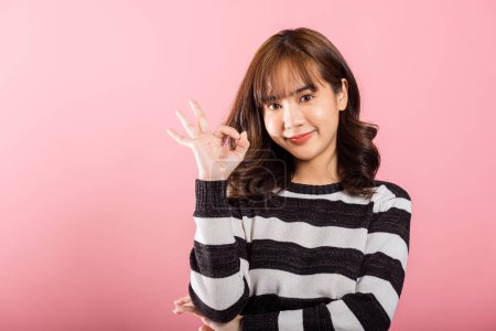 Téléchargez les photos : Portrait d'une jeune femme asiatique heureuse faisant le signe OK d'accord. Studio tourné isolé sur fond blanc, présentant un style de vie positif avec espace de copie. - en image libre de droit