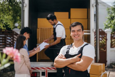Photo for In a portrait a happy mover unloads boxes from a truck into a new home. These workers show teamwork ensuring a smooth relocation and happiness. Moving day concept - Royalty Free Image