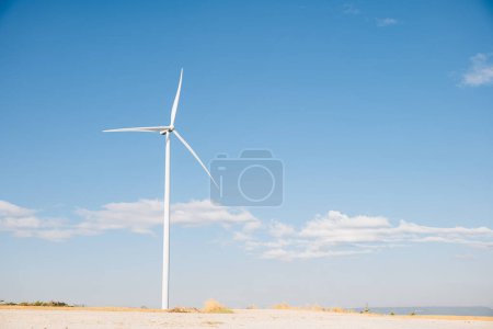 Photo for On a mountain windmill farm turbines harness natures wind for clean energy. Modern innovation in wind technology drives sustainable development under the expansive blue sky. - Royalty Free Image